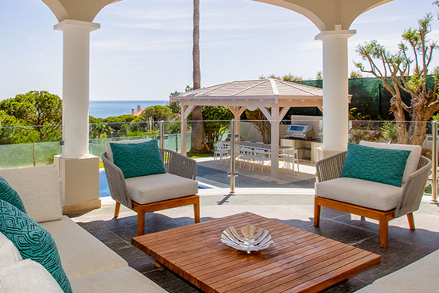 Covered outdoor lounge with pale sofas and garden views