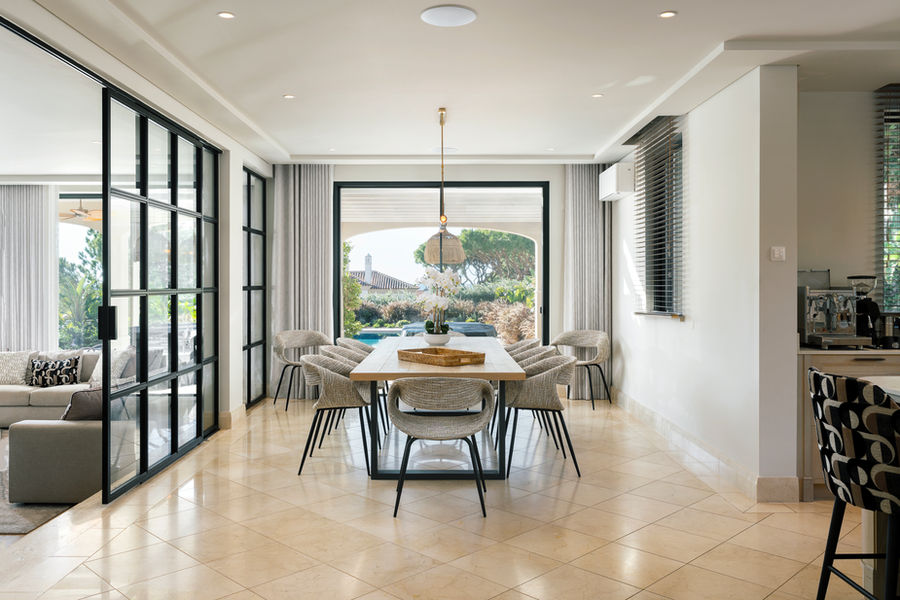 Dining area with garden views through black-framed glazing — Dunas Douradas