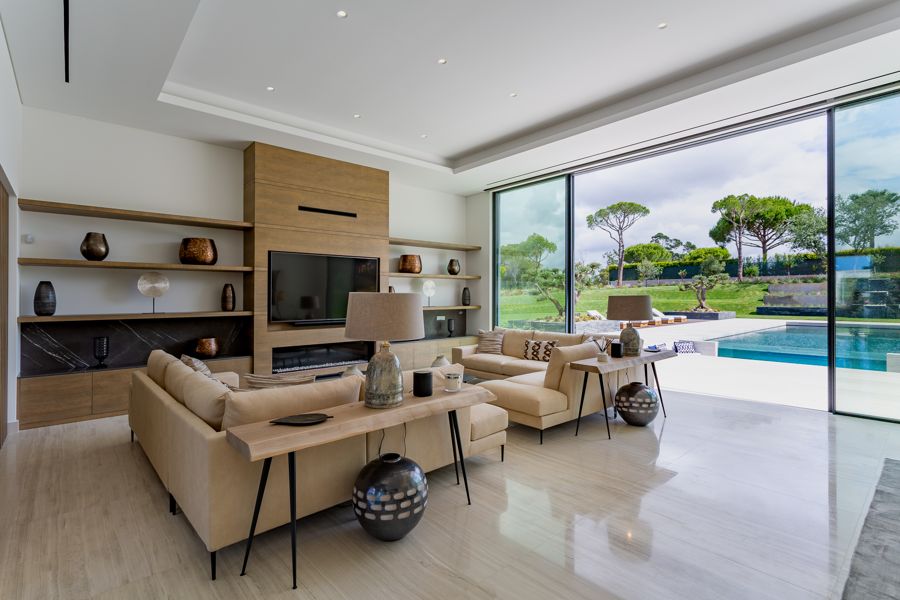 Living room with oak media wall and pool views — Pinhal Velho, Vilamoura
