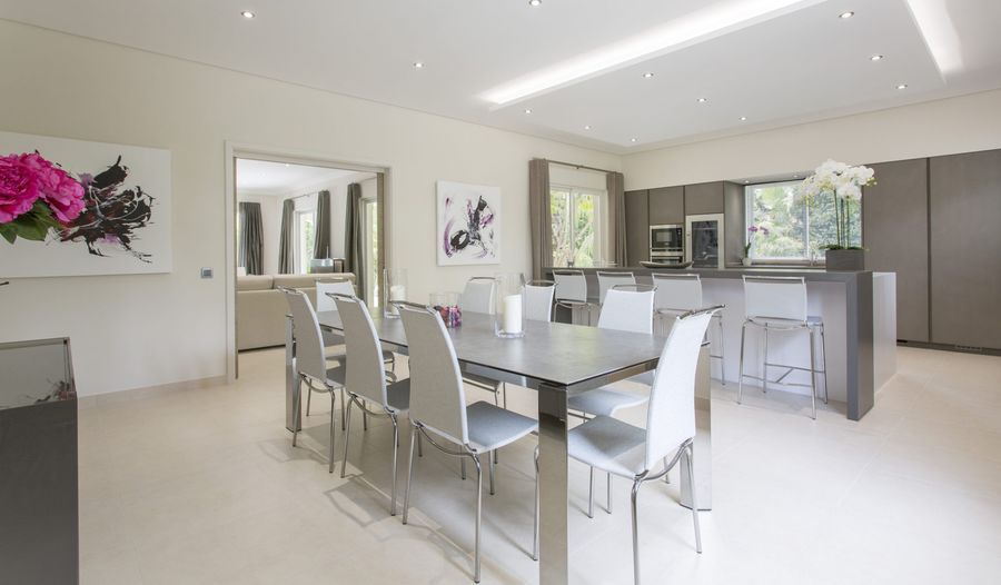 Open-plan dining table with white chairs and kitchen island — Quinta Verde, Algarve