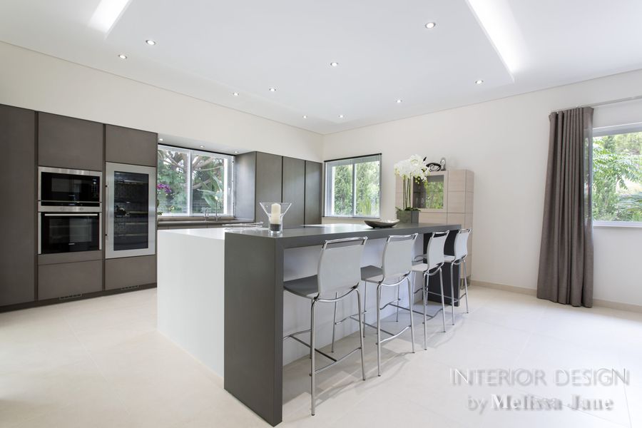 Kitchen with dark cabinetry, integrated ovens and island barstools — Quinta Verde, Algarve